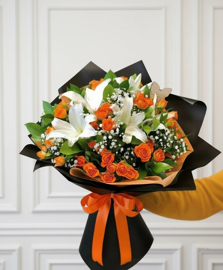 Bouquet of flowers with orange and white flowers held by a person in a blurred indoor setting